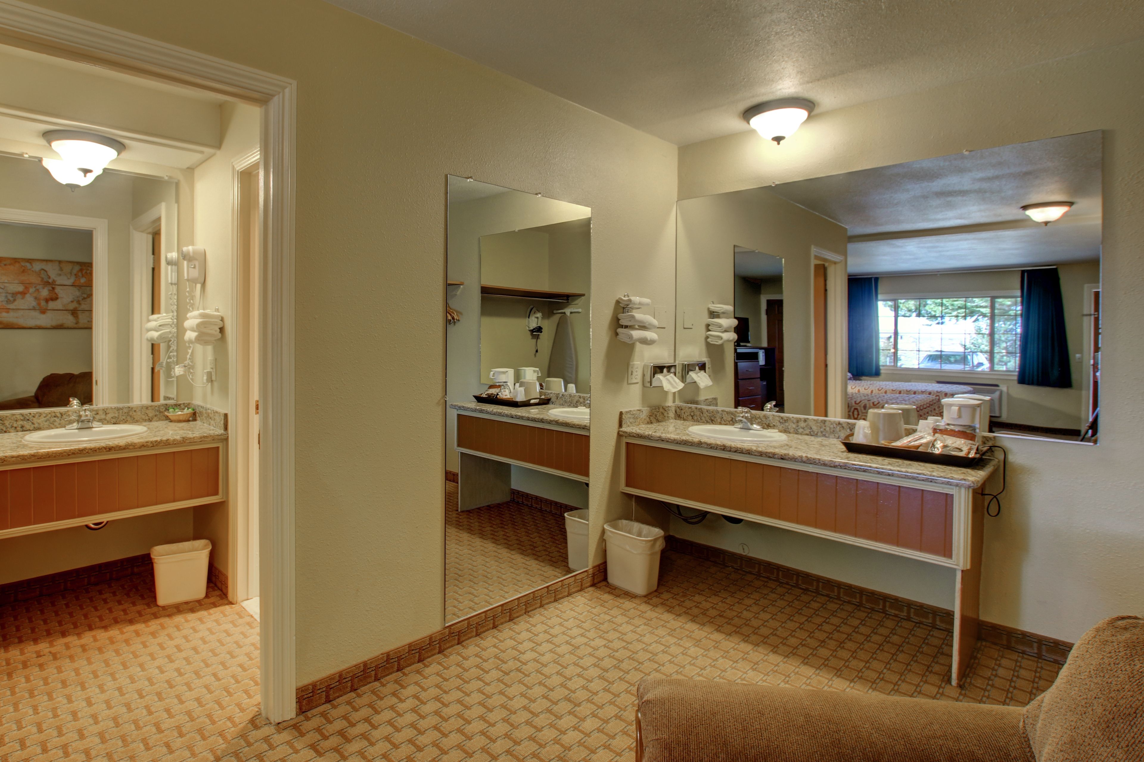 Un baño de hotel con dos lavamanos, un espejo grande y un perchero para toallas.