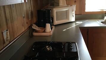Eine Küche mit Holzausstattung, einer Mikrowelle, einer Kaffeemaschine und einem Gasherd.