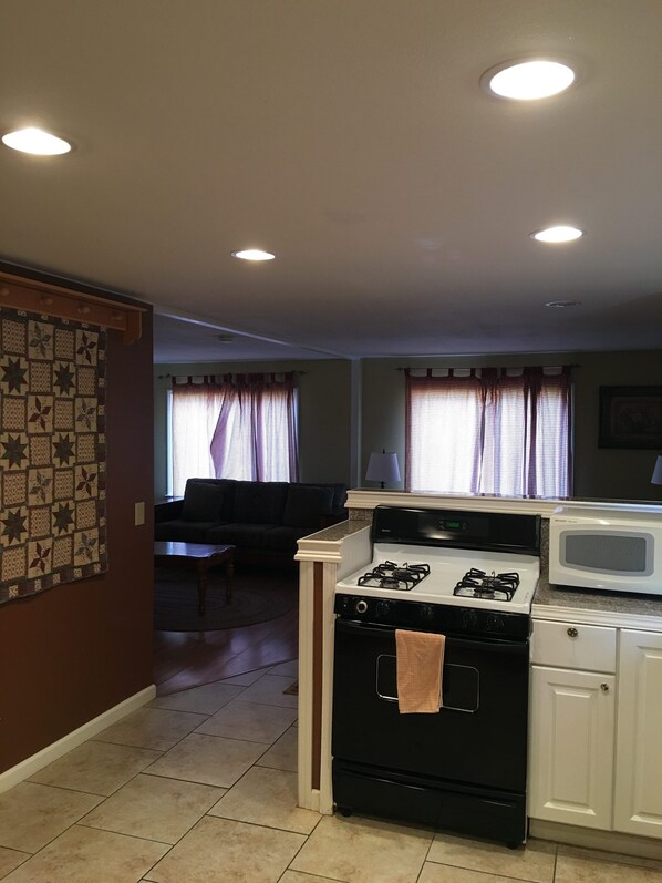 Cocina compacta con estufa, microondas y zona de comedor con sofá.