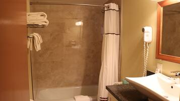 A bathroom with a glass-enclosed shower, a white sink, and a hairdryer mounted on the wall.