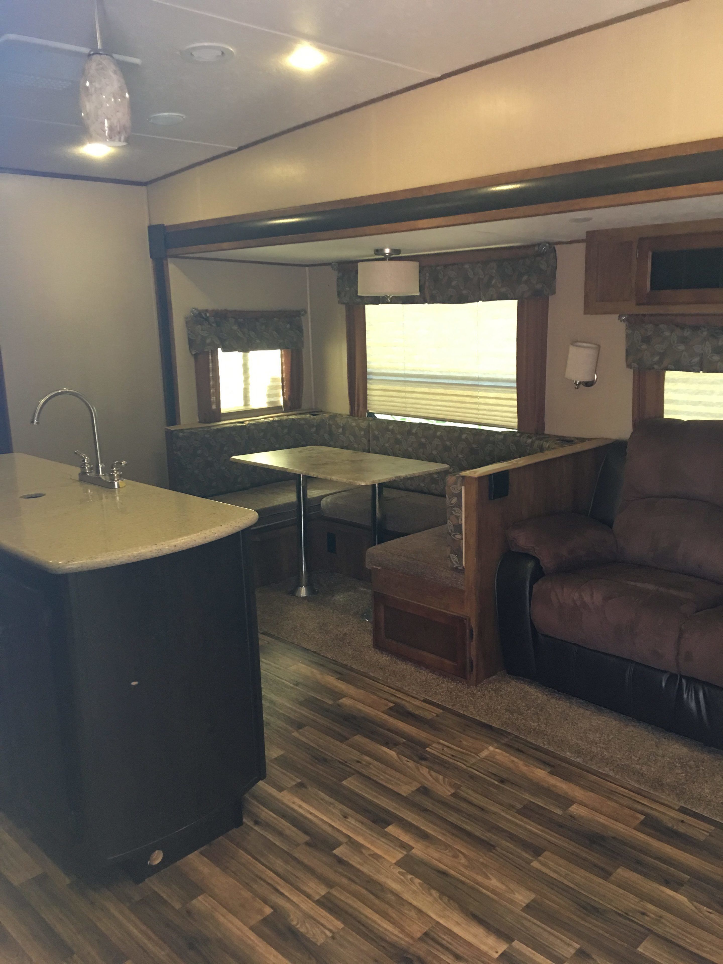 A compact RV interior with a kitchenette, seating area, and a window providing natural light.