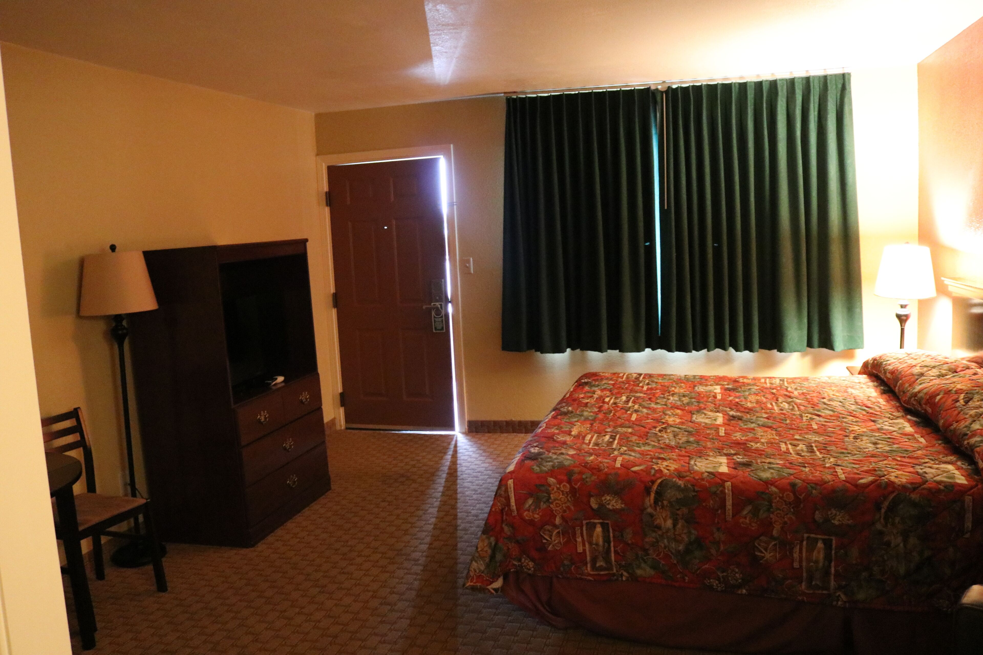 Una habitación de hotel con cama, cómoda, escritorio, silla y puerta.