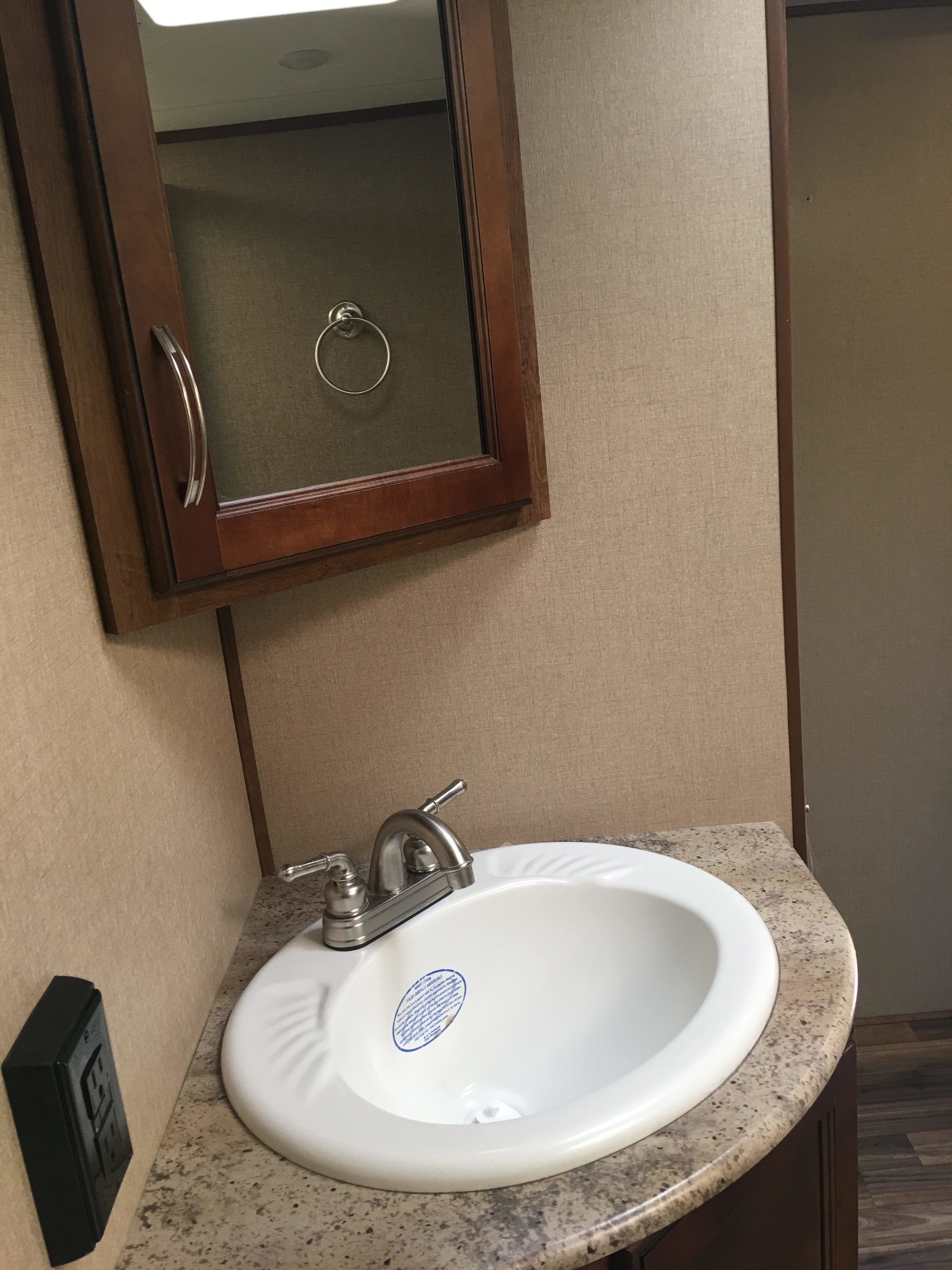 A bathroom with a white sink, a mirror, and a wooden cabinet.