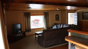 Una sala de estar con televisor, sofá, mesa de centro y una zona de bar.