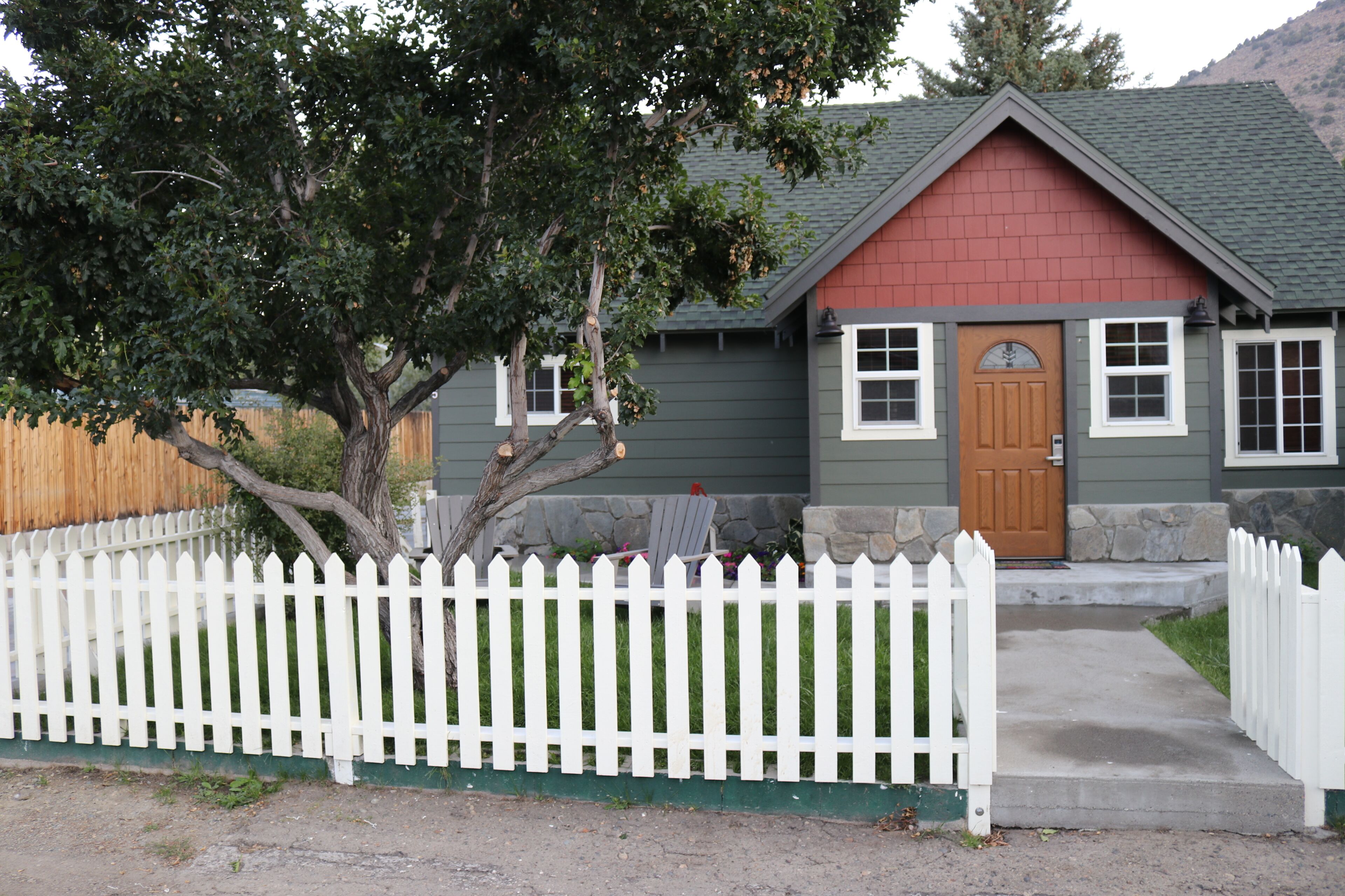 A house with a white picket fence, a red door, and a grey roof.
