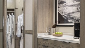 Une salle de bain moderne avec des meubles en bois, un grand miroir, une photographie encadrée et une machine à café.