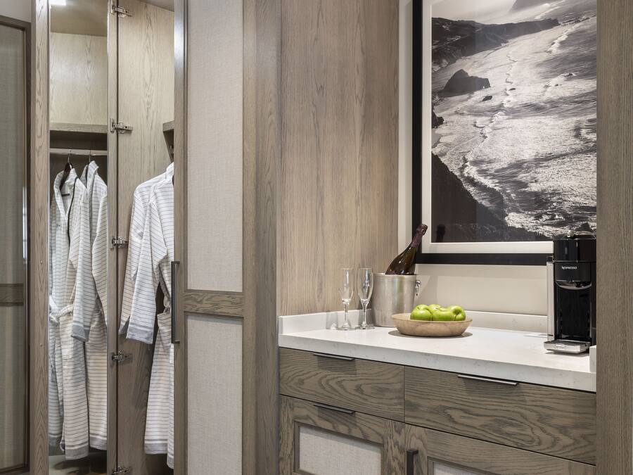 A modern bathroom with wooden cabinetry, a large mirror, a framed photograph, and a coffee machine.