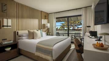Een moderne hotelkamer met een groot bed, een bureau, een stoel en een balkon met uitzicht.