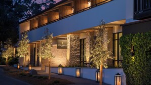 Un hôtel au design moderne, caractérisé par une façade en pierre, des balcons en bois et une entrée bien éclairée.