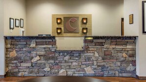 A reception area with a stone wall, a large C-shaped logo, and framed certificates on the wall.