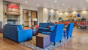 A hotel lobby with a stone fireplace, blue sofas, and a bar area.