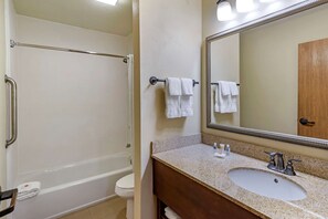 A bathroom with a bathtub, toilet, sink, and a large mirror.