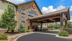 A Comfort Inn & Suites building with a stone facade, a covered entrance, and a landscaped driveway.