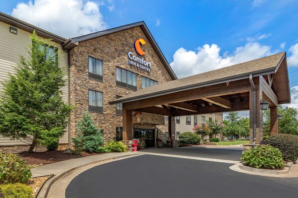 A Comfort Inn & Suites building with a stone facade, a covered entrance, and a landscaped driveway.