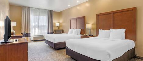 A hotel room with two beds, a desk, a TV, and a window with curtains.