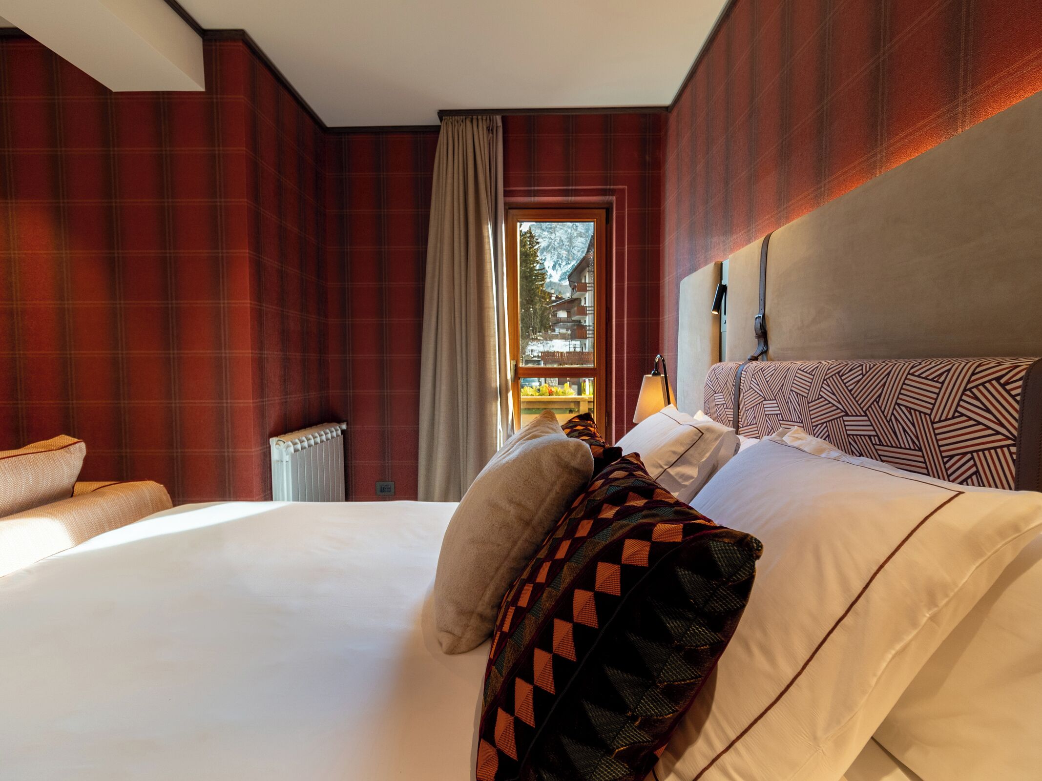 Habitación de hotel con una cama grande, vistas al exterior y una ventana con cortinas.