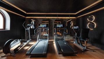 Een fitnessruimte met loopbanden, elliptische trainers en een spiegelwand.