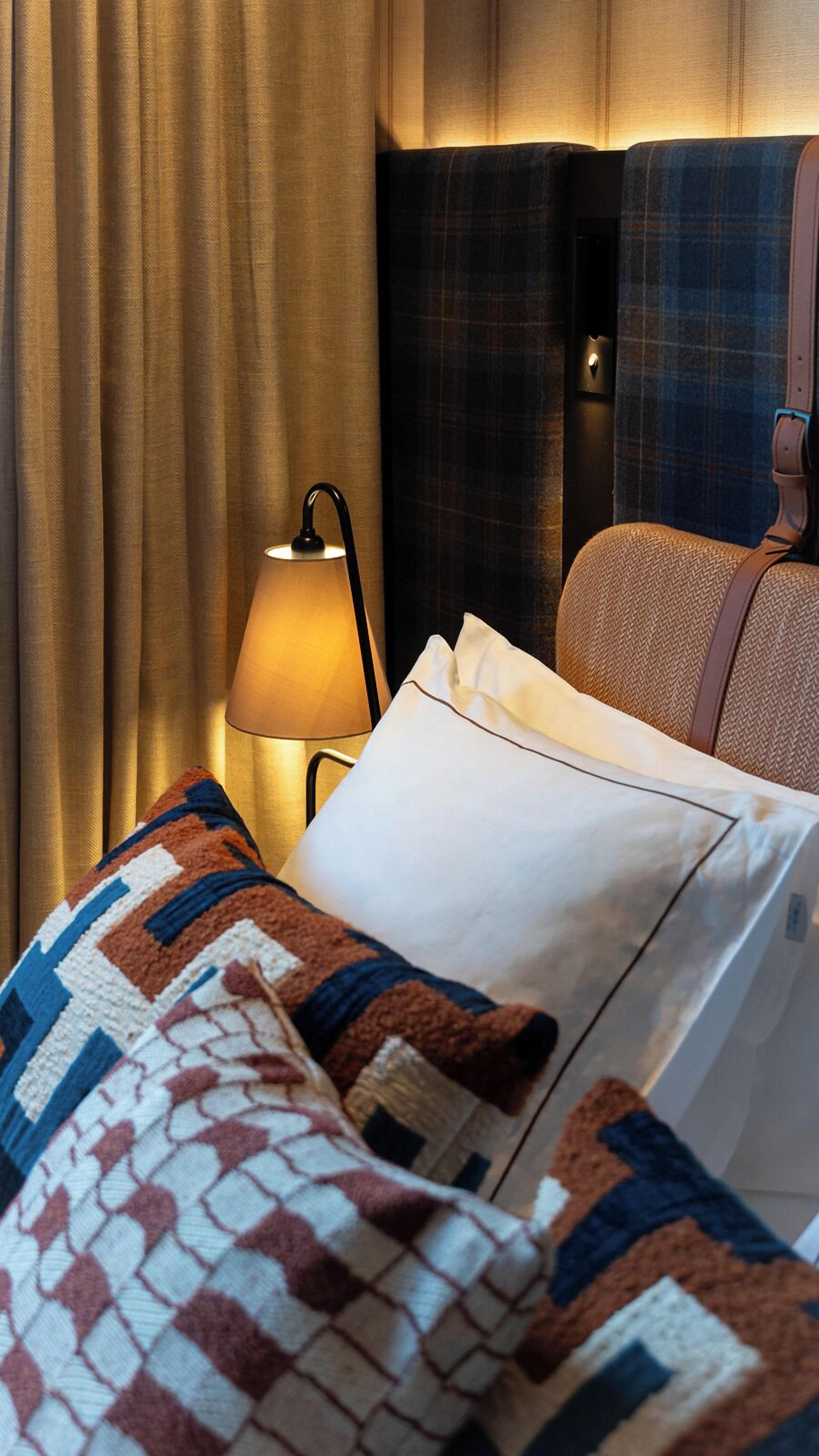 Una habitación de hotel con cama, lámpara y cabecero.