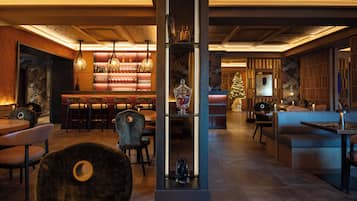 A modern bar area with a wooden ceiling, bar stools, and hanging pendant lights.