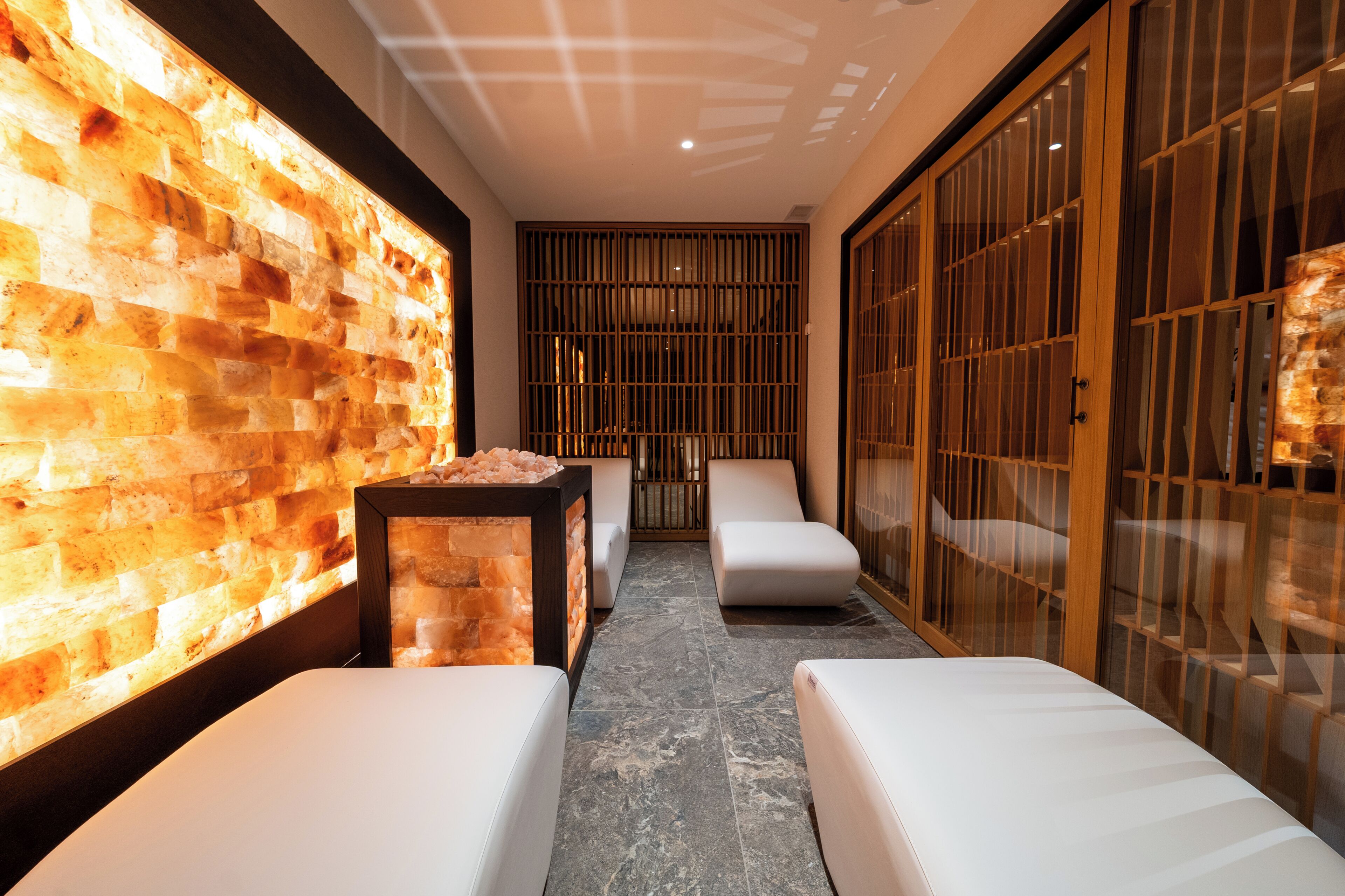 Un área de spa con pared de piedra, asientos y una lámpara de sal.
