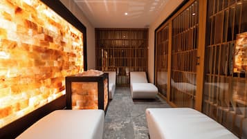 Un área de spa con pared de piedra, asientos y una lámpara de sal.