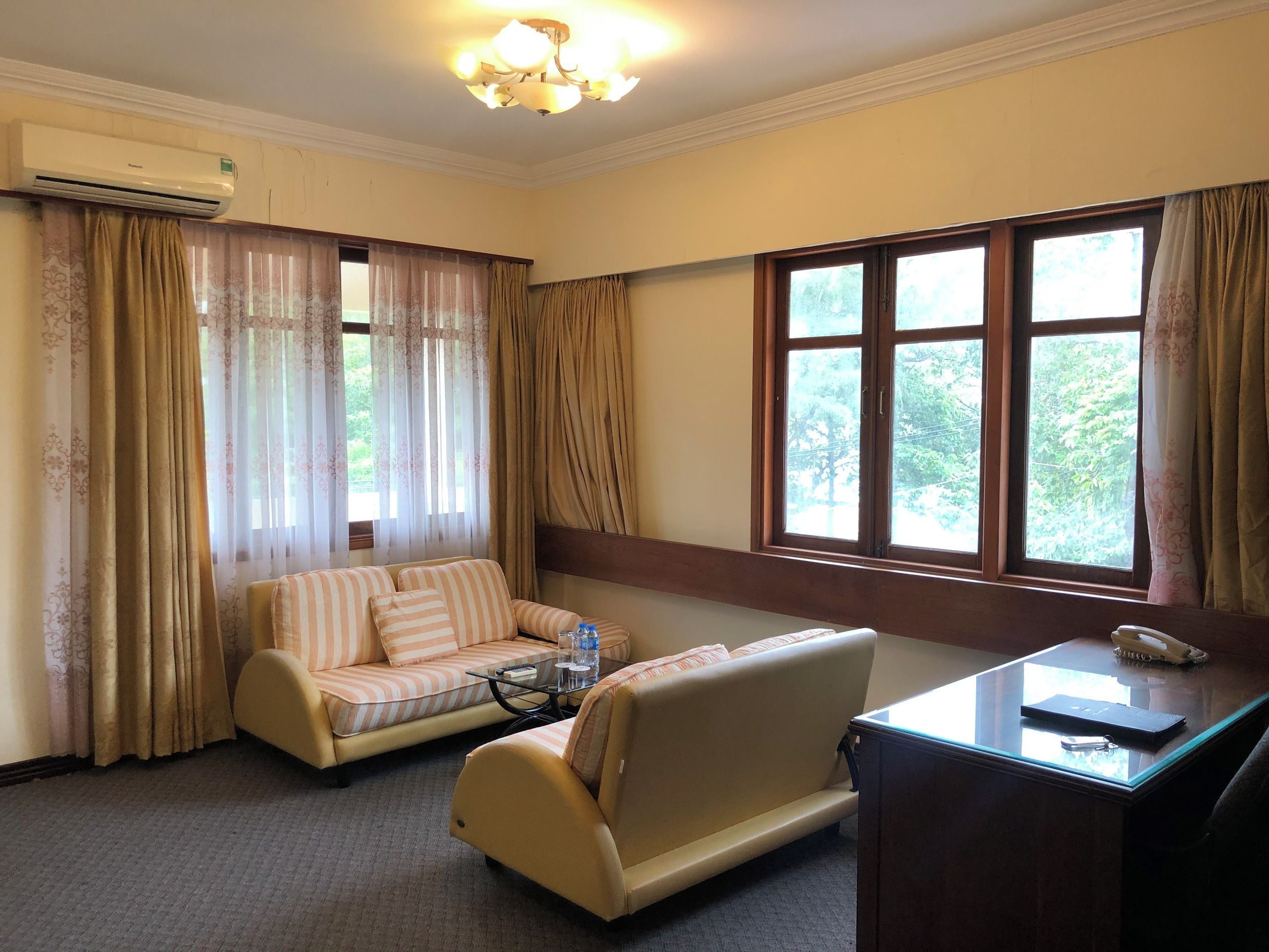Una habitación con sofá, escritorio y ventana con cortinas.