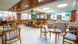 Eine Hotelhalle mit Holzmöbeln, einer Bar und großen Fenstern.