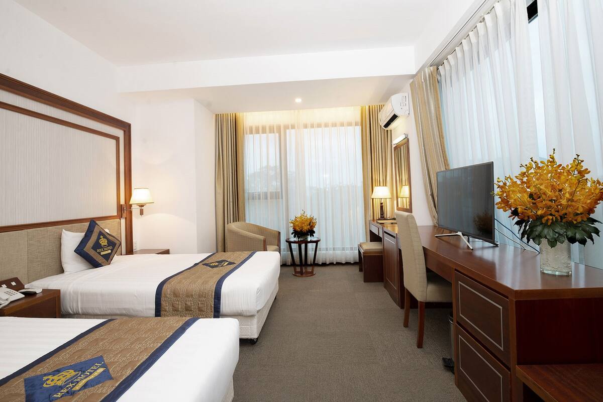 Una habitación de hotel con dos camas, un escritorio, un televisor y una silla.