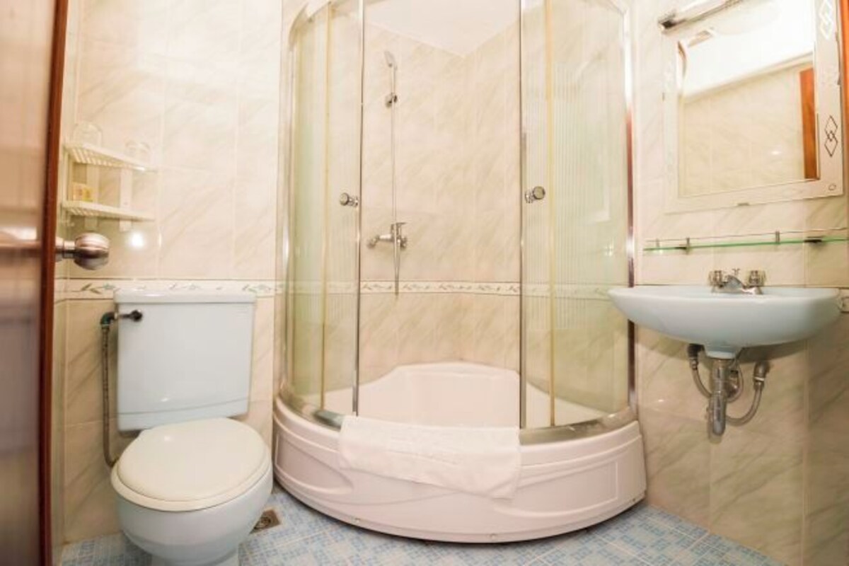 A bathroom with a glass-enclosed shower, a toilet, and a sink.