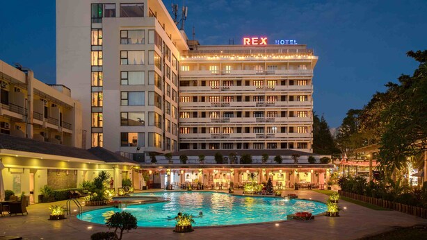 Ein Hotel mit Schwimmbad, mehreren Etagen und einem Schild mit der Aufschrift 'REX HOTEL'.