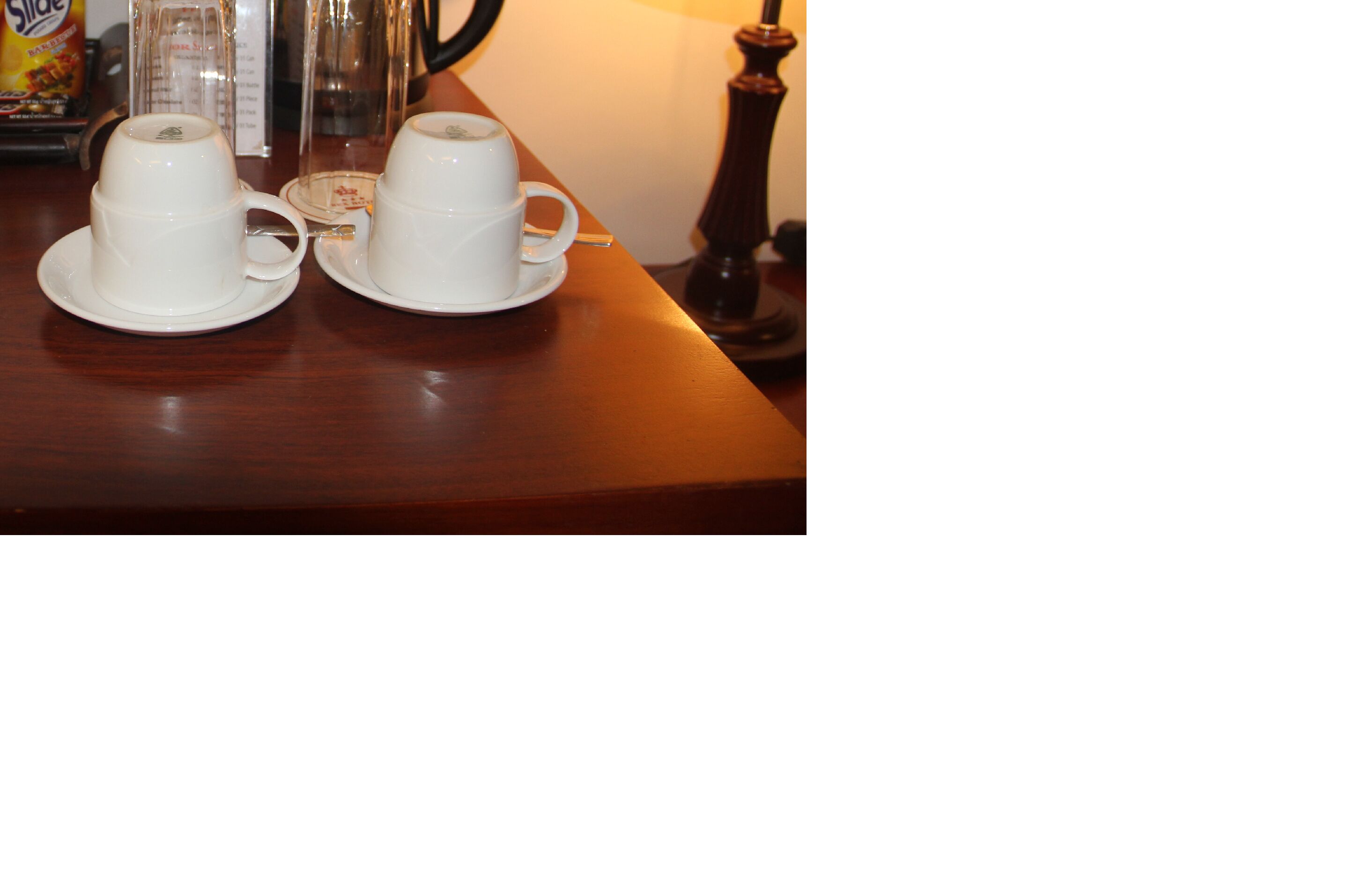 Two white cups on saucers on a wooden table.
