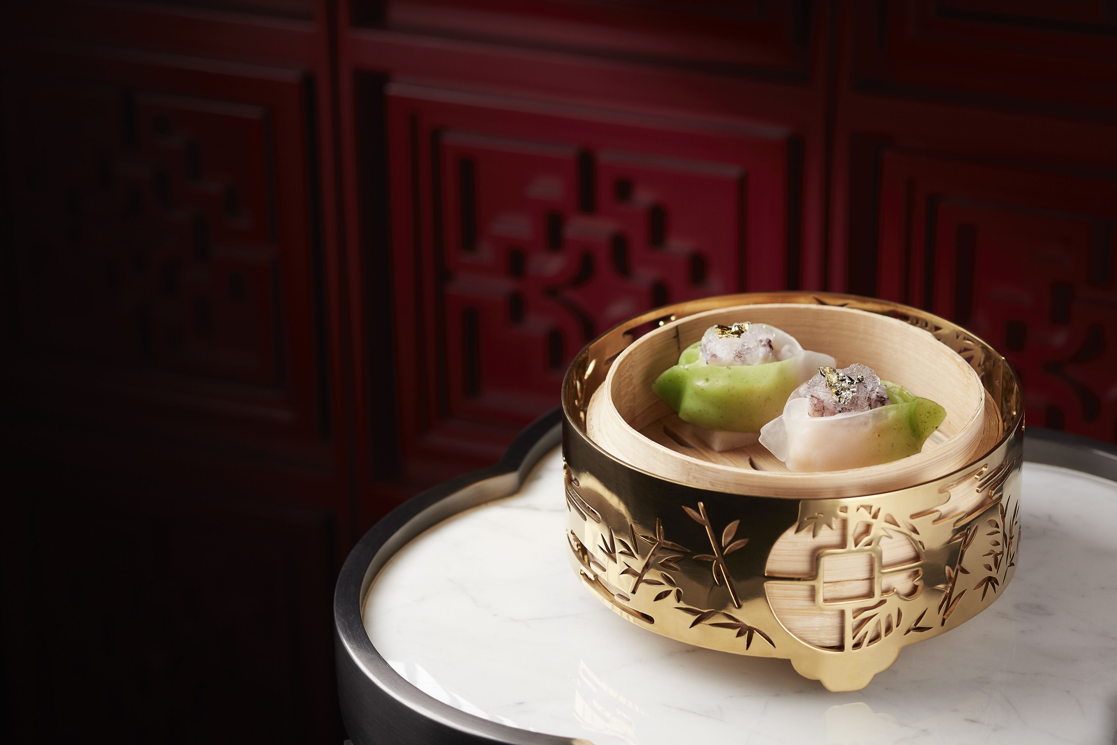 A traditional Chinese dim sum dish in a decorative bowl on a marble table.