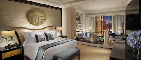 A hotel room with a large bed, a bench, a desk, a TV, and a balcony with a city view.