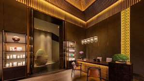 Un moderno área de recepción con un mostrador de madera, sillas y una exhibición de artículos de tocador.