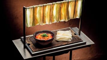 A table with a bowl of soup and sliced vegetables on a tray.