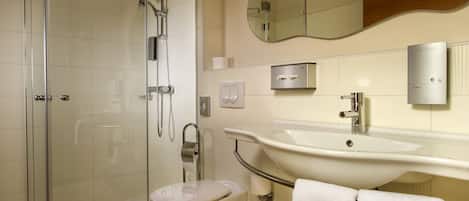 A modern bathroom with a glass-enclosed shower, a toilet, a sink with a towel rack, and a mirror above the sink.
