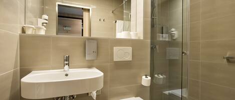Un baño moderno con lavamanos, inodoro y ducha con mampara de vidrio.