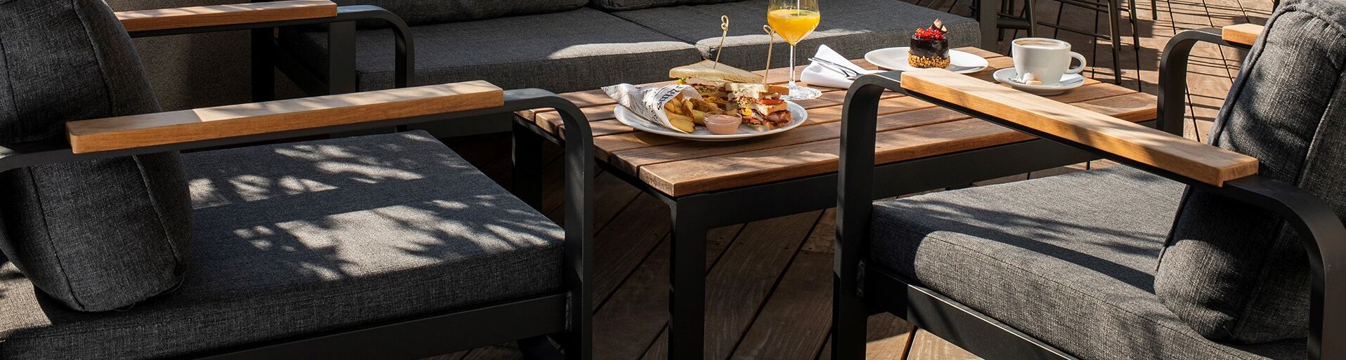 A cozy outdoor seating area with wooden tables and grey upholstered chairs.