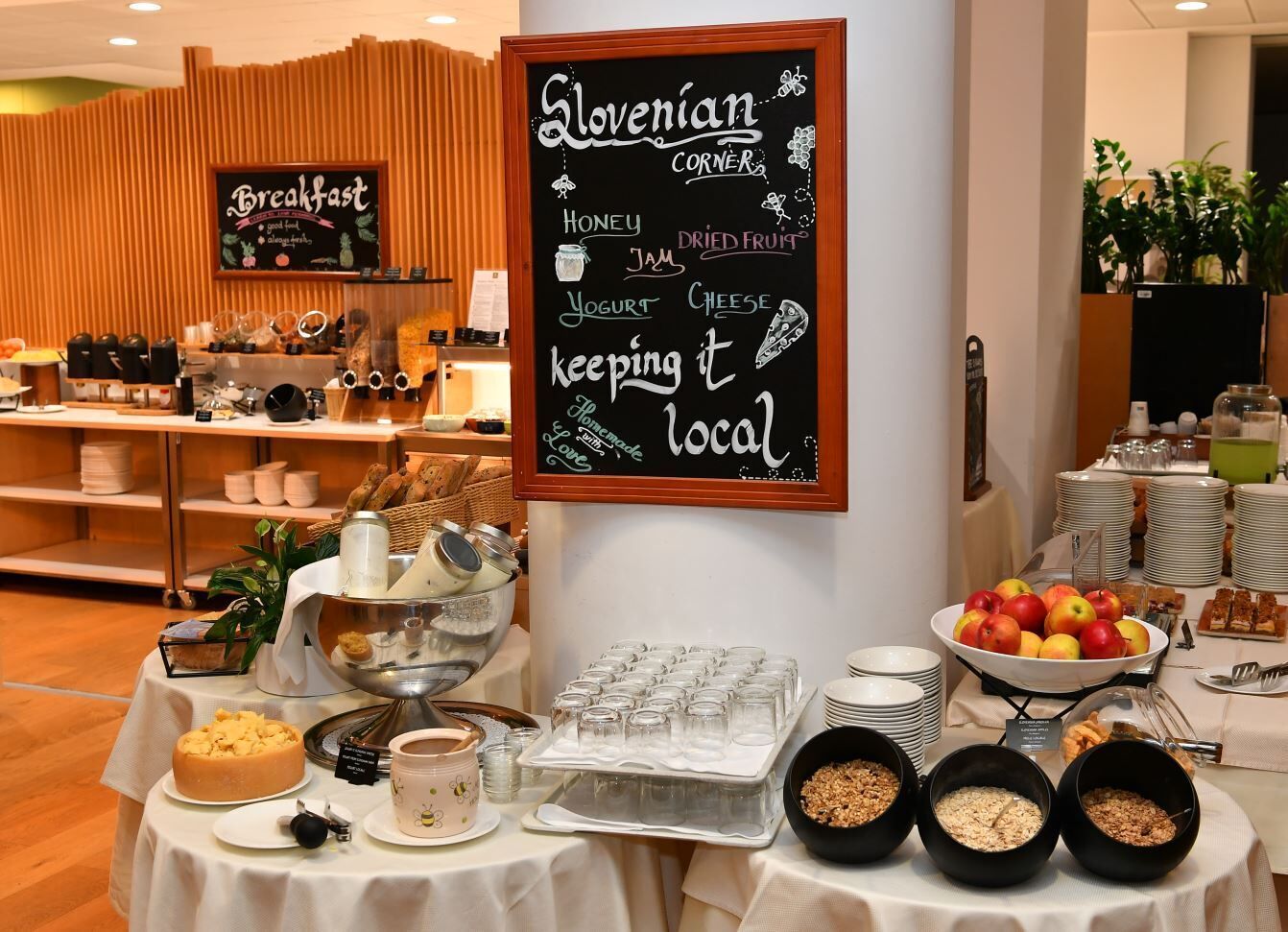 A breakfast buffet with a chalkboard sign listing items like honey, jam, yogurt, and cheese.