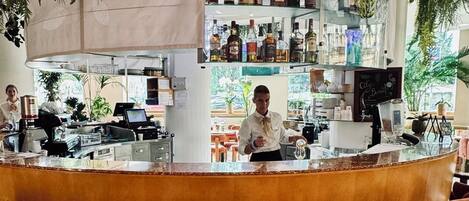 Zona de bar con mostrador, taburetes y estantes llenos de botellas.