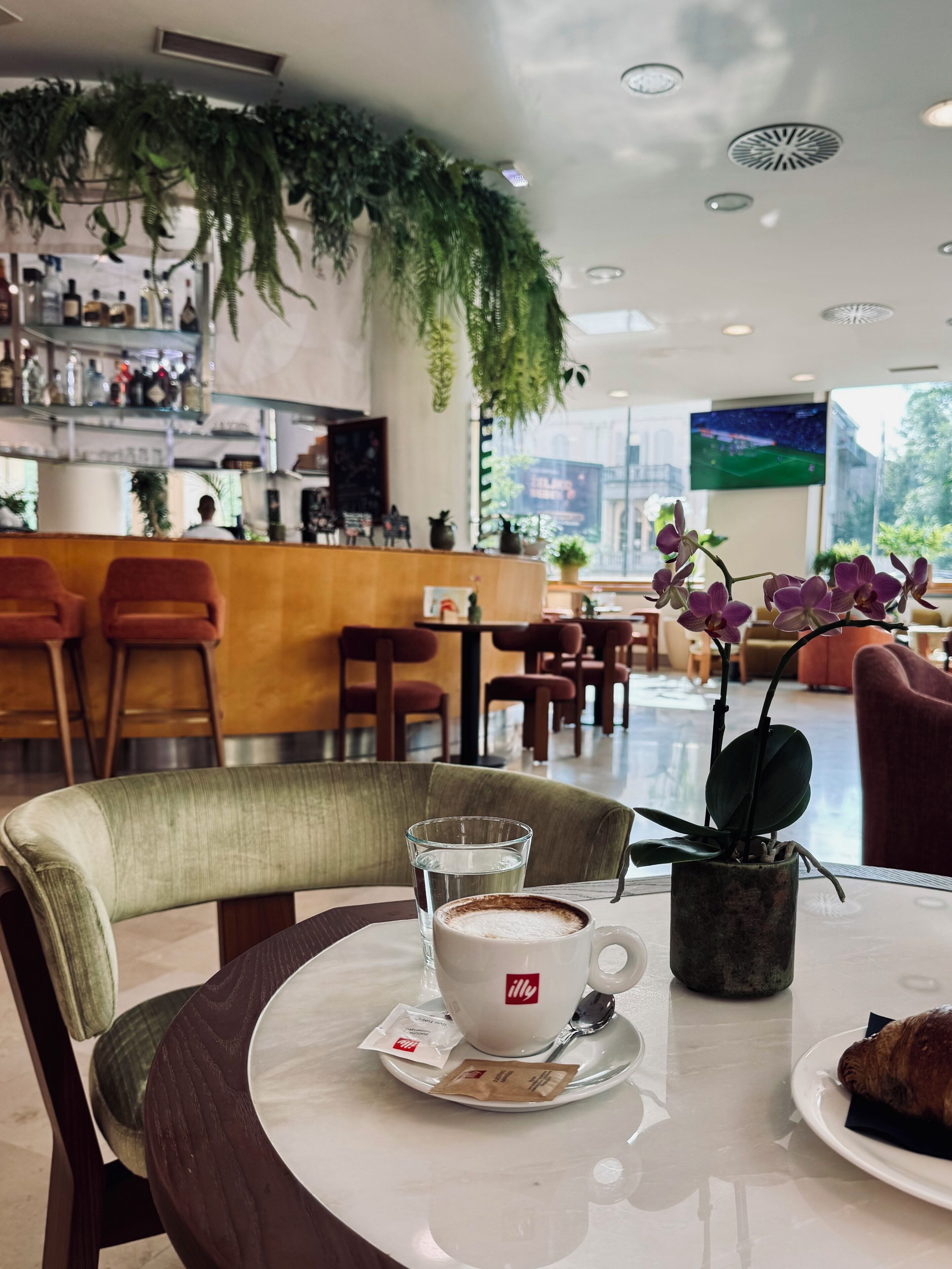 A cafe setting with a table, chairs, a coffee cup, a pastry, and a bar area in the background.