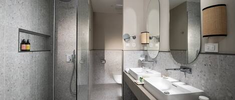 A modern bathroom with a glass-enclosed shower, a large mirror, and a vanity with a sink and towel rack.