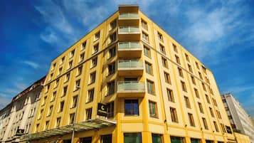 A multi-story hotel with balconies, a clear sky, and a sign indicating it is a city hotel.