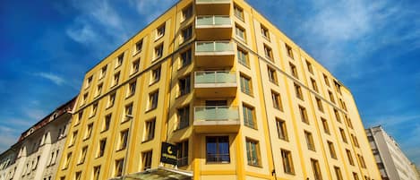 A multi-story hotel with balconies, a clear sky, and a sign indicating it is a city hotel.
