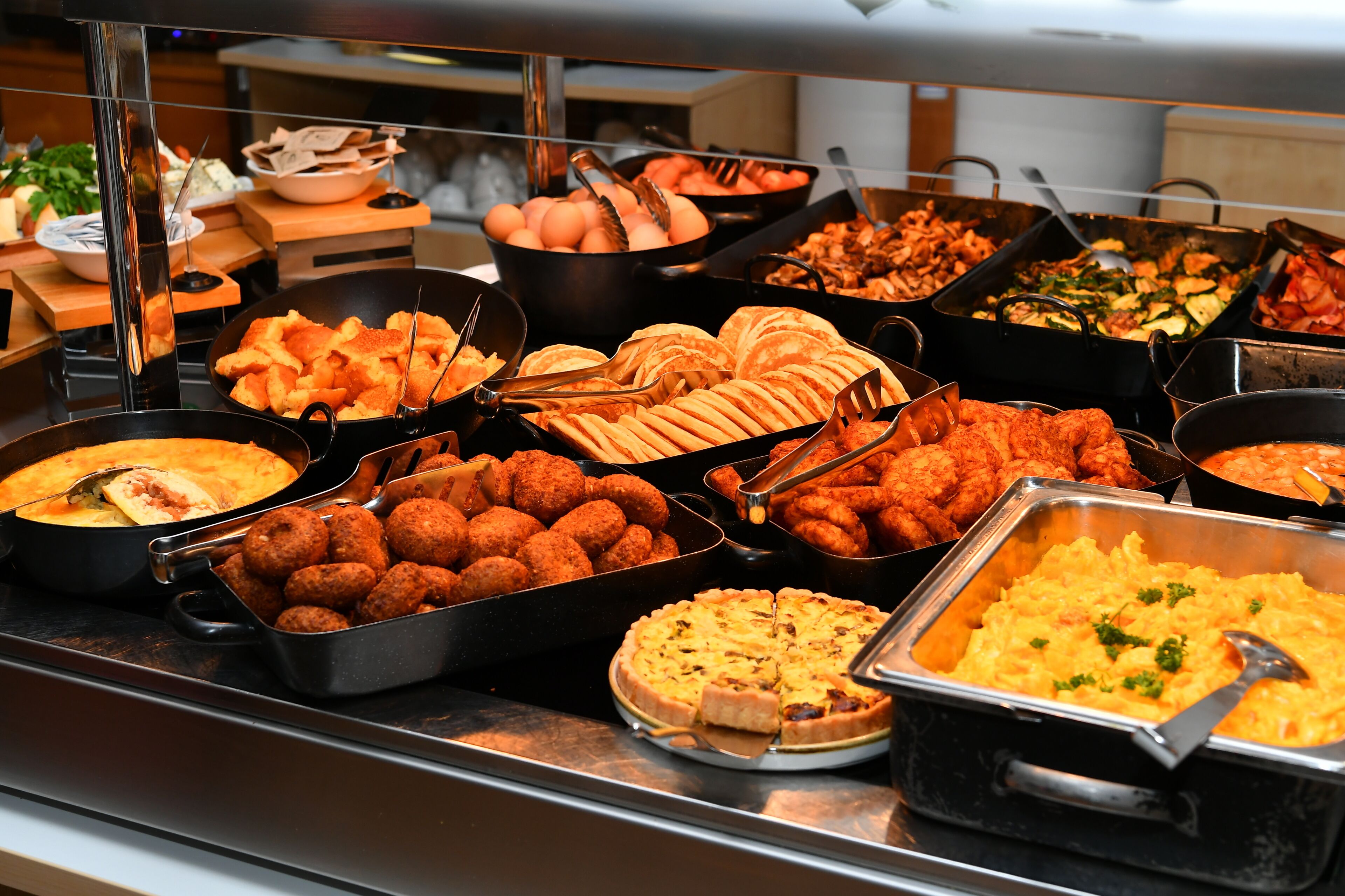En buffet med forskellige spiser, heriblandt kød, oste og friskbagt brød.