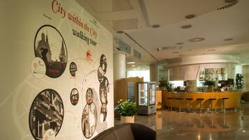 A lobby with a large wall featuring historical cityscape photos, a seating area, and a bar.