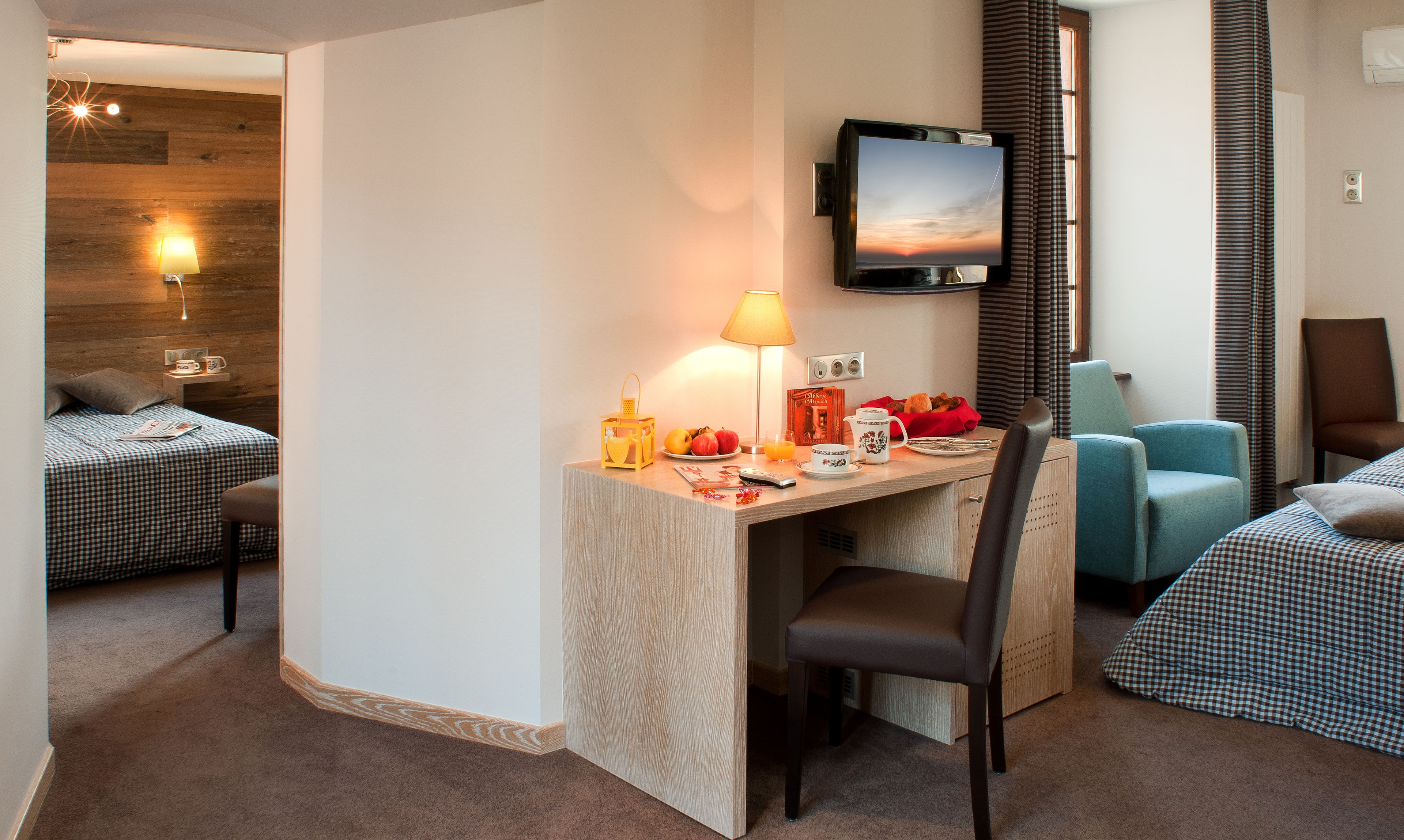 Een hotelkamer met een bureau, een televisie, een bed en een stoel.