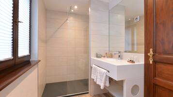 Un baño moderno con ducha, lavabo con espejo y puerta de madera.