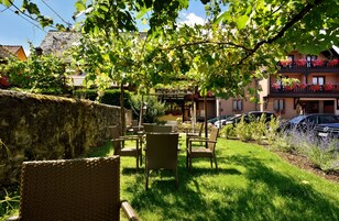 A courtyard with wicker furniture, a stone wall, and a building with balconies.