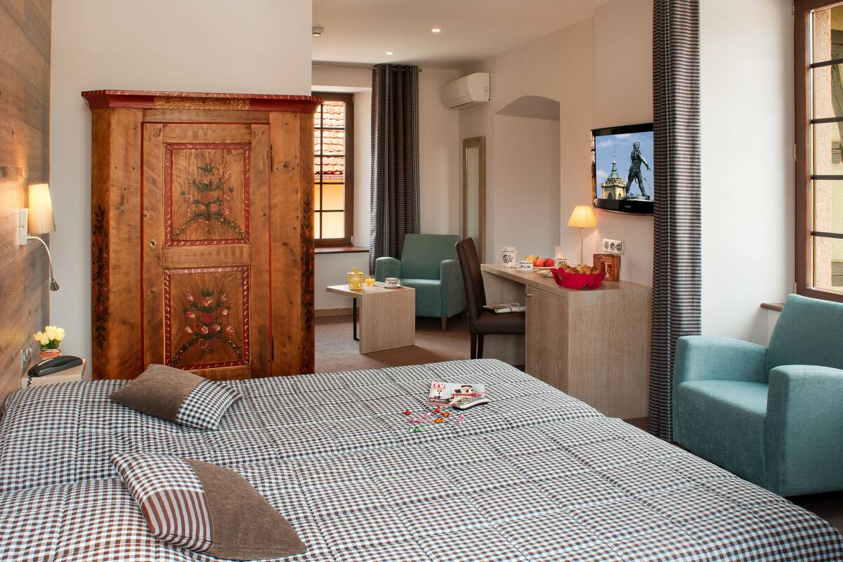 A hotel room with a large bed, a desk, a chair, and a television.